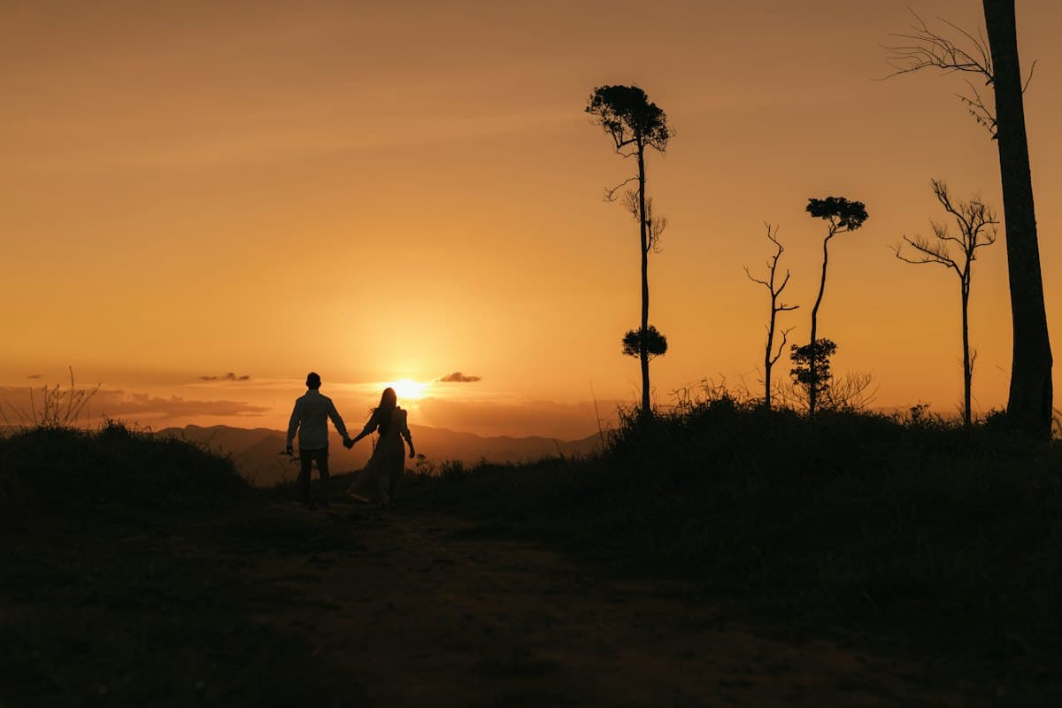 A couple walking hand in hand at sunset