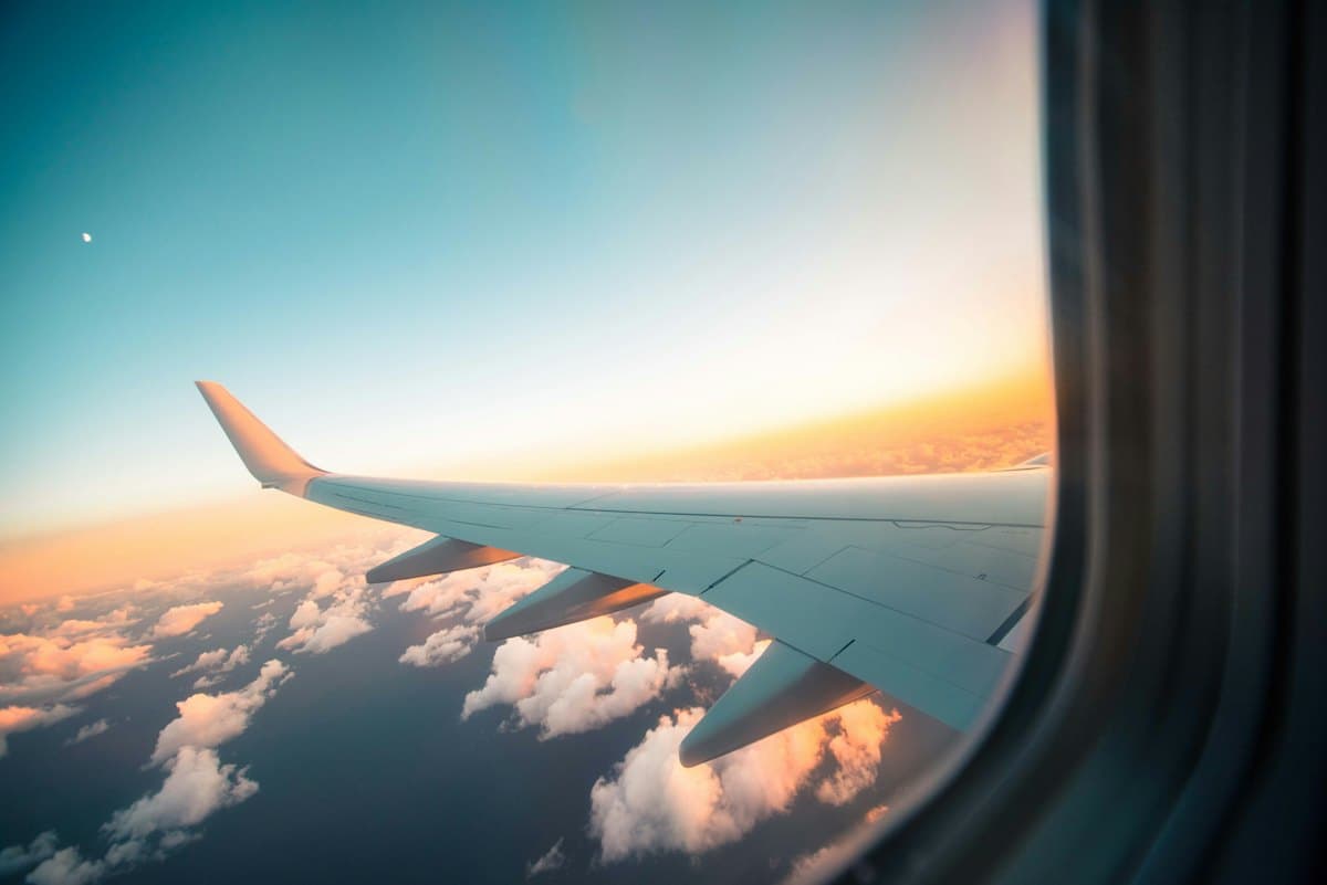 Aircraft wing seen from the cabin window above the clouds