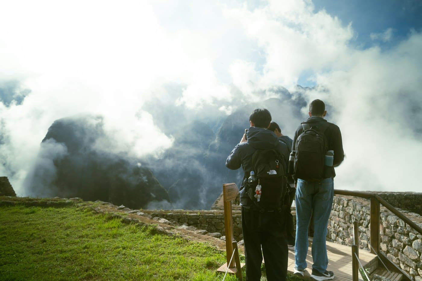 Two travellers with backpacks looking out over misty mountains