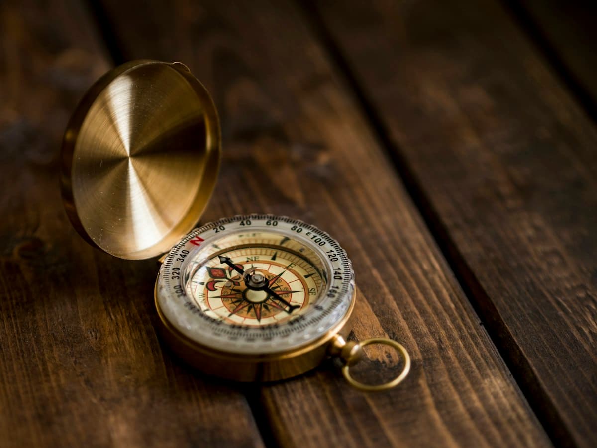 A brass compass on a wooden table