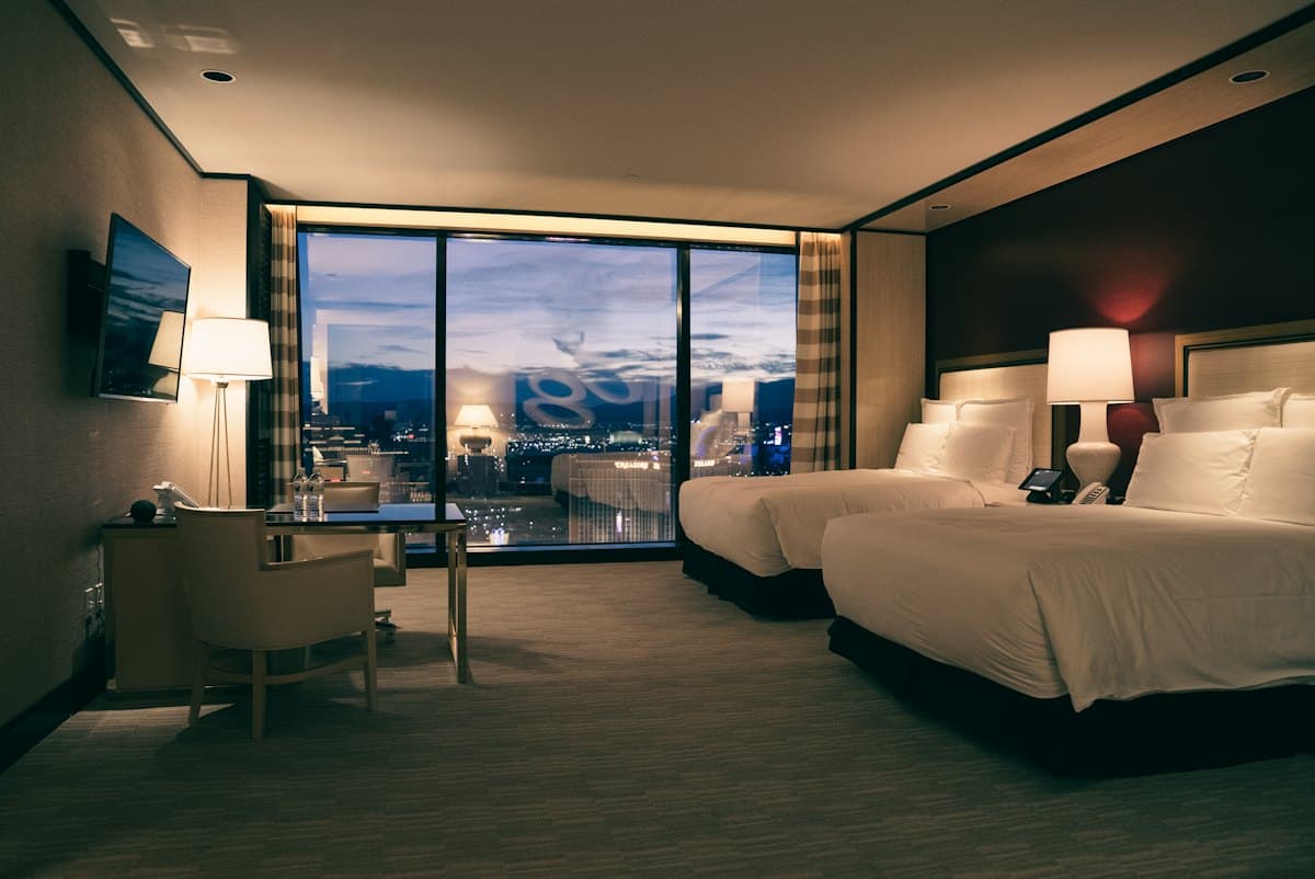 A hotel room with two beds and a city view