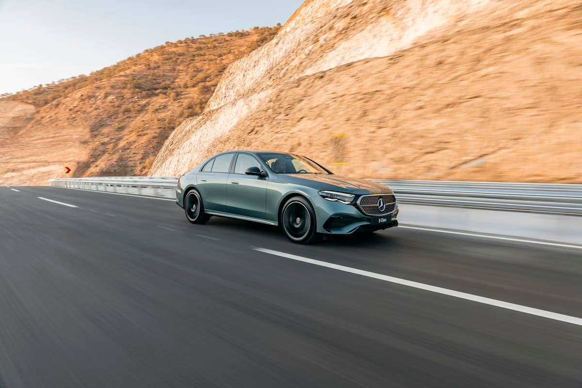 A premium sedan driving on a highway through the hills