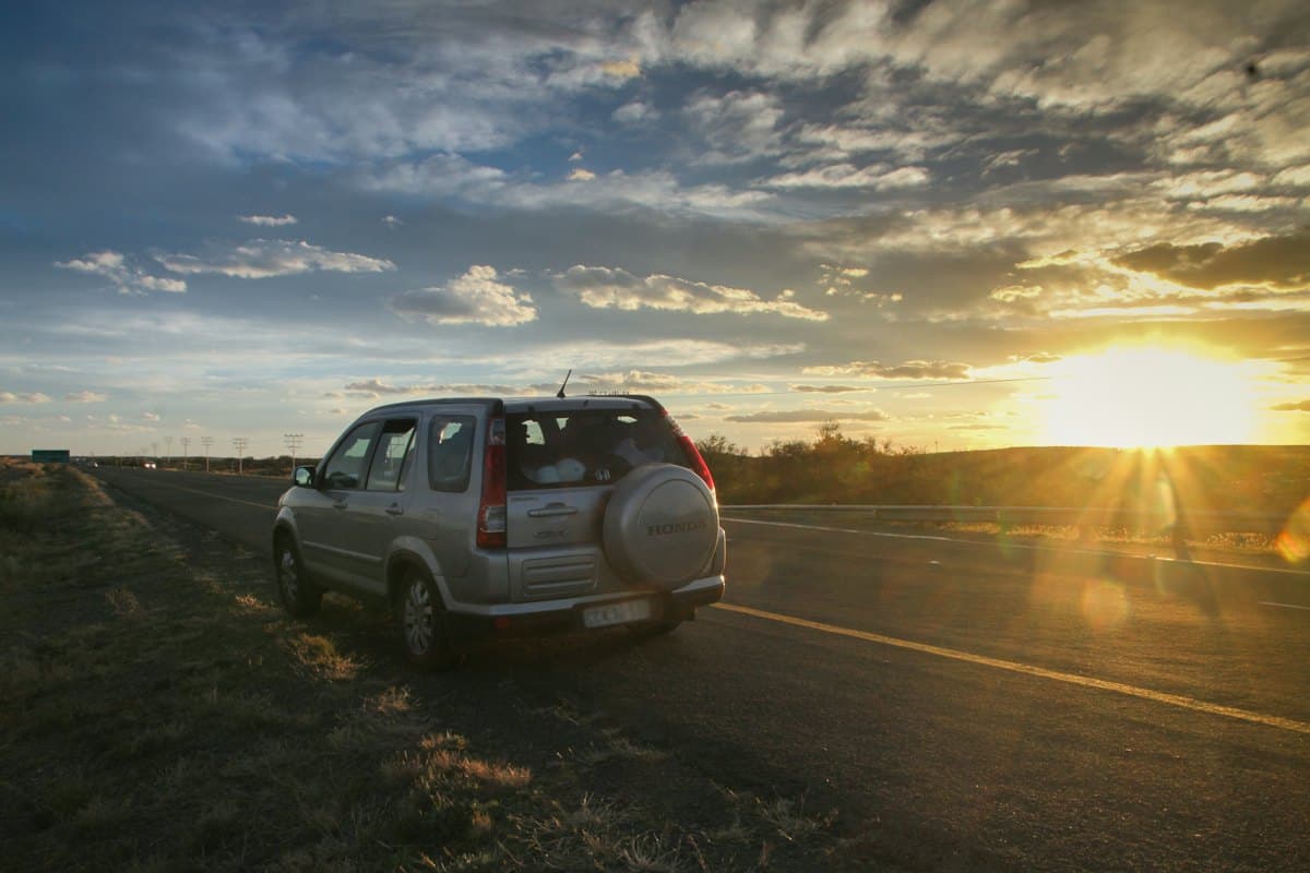An SUV on an open road at sunset